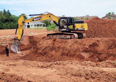Excavator digging red dirt in PEI. Landmark Construction PEI.