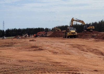 Heavy machinery building a new road with red dirt in PEI.