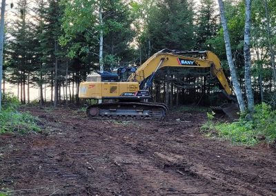 Yellow SANY excavator clearing forested land. Landmark Construction PEI.