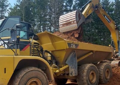 Large CAT dump truck filled with earth from excavator. Landmark Construction PEI.